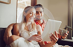 This is how we spend our days. a young couple using a digital tablet together at home.