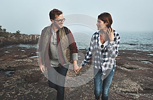 This is how they spend their Sundays. a cheerful young couple holding hands and walking together next to the ocean