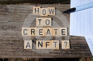 How to create a NFT? Black capital letter words on wooden toy blocks on a natural garden table background with paper and pencil. photo