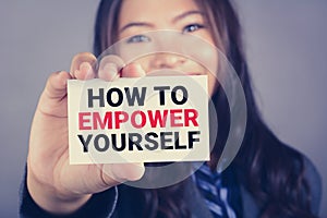 HOW TO EMPOWER YOURSELF message on the card shown by a businesswoman