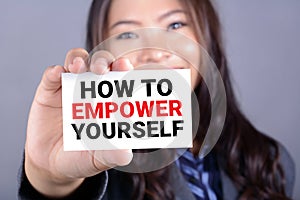 HOW TO EMPOWER YOURSELF message on the card shown by a businesswoman