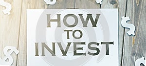 How to invest words written on copybook page and paper dollar signs around. Saving and investment business concept