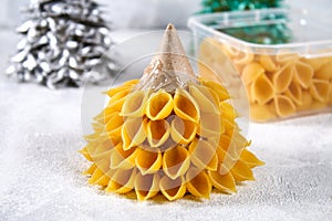 How to make a Christmas tree from raw pasta conchiglie. The process of making Christmas trees from pasta, cardboard plates, hot