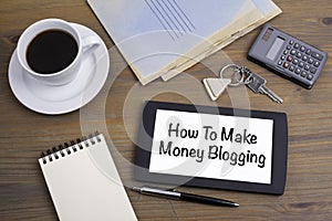 How to make money blogging. Text on tablet device on a wooden ta