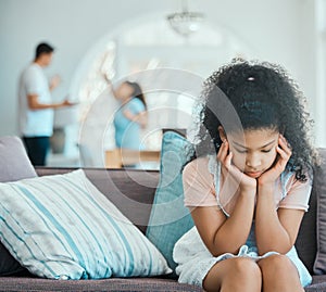 How to make your daughter resentful. a little girl looking sad on a sofa while her parents argue in the background.