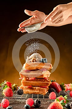 How to powdering traditional homemade waffles with icing sugar. Waffles with ice cream, caramel sauce and fresh berries. Delicious