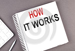 HOW IT WORKS text on the notebook with calculator and pen