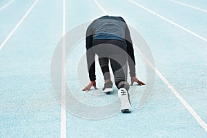 How you start is important. Rearview shot of an unrecognizable young male athlete in the set position out on the running