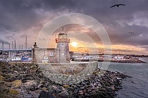 Howth Lighthouse with flying seagulls at beautiful sunset