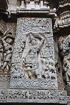 Hoysaleswara Temple outside wall carved with sculpture of Lord krishna lifting govardhana giri