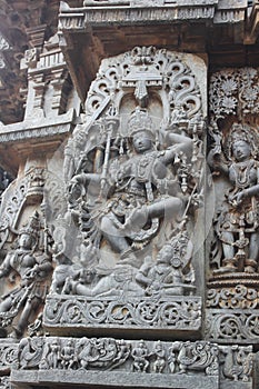 Hoysaleswara Temple outside wall carved with sculpture of lord shiva dancing on top of a demon