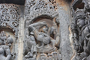 Hoysaleswara Temple wall carved with sculpture of Darpana Sundari beautiful lady with mirror