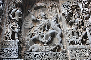 Hoysaleswara Temple wall carved with sculpture of Garuda humanoid bird fighting with Nagas Serpents