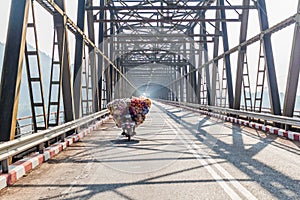 HPA AN, MYANMAR - DECEMBER 13, 2016: Local man on a heavily loaded motorbike crosses a bridge over Thanlwin Thanlyin river near