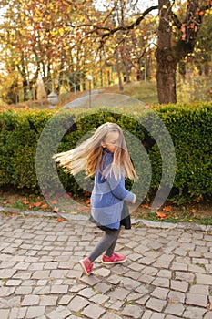 Hppy little girl dance in the park. She spend time in anutumn day in the park