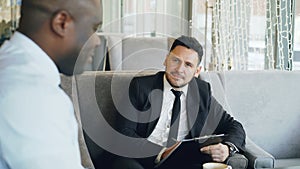 HR businessman having job interview with african american man and watching his resume application in modern cafe