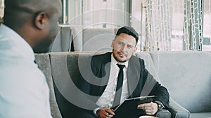 HR businessman having job interview with african american man and watching his resume application in modern cafe
