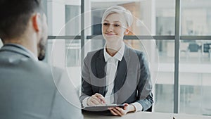 HR businesswoman having job interview with young man in suit and watching his resume application in modern office