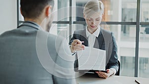 HR businesswoman having job interview with young man in suit and watching his resume application in modern office