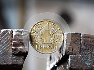 Hryvnya coin clamped in a metal vise. Currency and Ukrainian economy under the onslaught, the concept of financial problems and