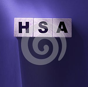 HSA abbreviation on wooden cubes on red. Concept. Health Savings Account.