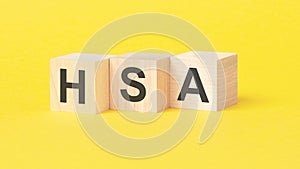 HSA - Health Savings Account symbol. wooden cubes with words. beautiful yellow background. business concept. copy space.