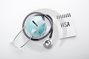 HSA word on note pad with piggy bank and stethoscope