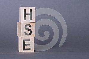 HSE - Health Safety Environment, text written on wooden blocks, on gray background