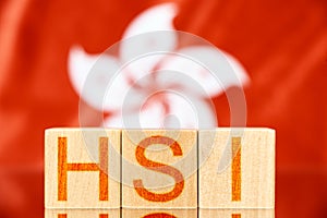 hsi index hong kong. wooden blocks with hsi lettering on hong kong flag background.