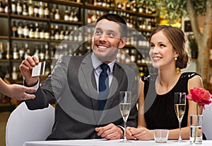 Hsppy couple paying with credit card at restaurant