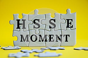 HSSE moment text on jigsaw puzzle with yellow background - Health, Safety, Security and Environment.