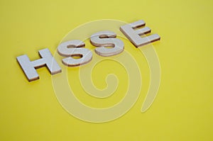 HSSE wooden letters representing Health, Safety, Security and Environment on yellow background