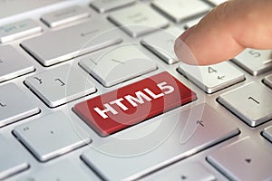HTML5 computer language. writing on button modern of gray laptop. Finger presses the button. Programmer for work.