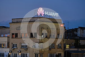 Huawei logo on top of a building with dilapidated exterior in Eastern Europe, at sunset. Bucharest, Romania - May 9, 2020