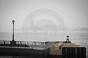 Hudson river docks under the rain overlooking the Statue of Liberty from the heart of Wall Street in Manhattan