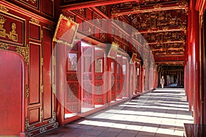 Hue / Vietnam, 17/11/2017: Woman passing through a red ornamental pavillion in the Citadel complex in Hue, Vietnam