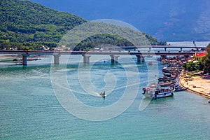 Beautiful aerial view with bridge, boats and mountains under a dramatic sky