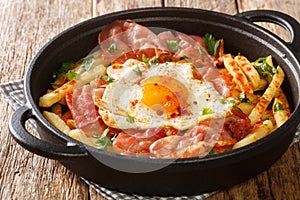 Huevos Rotos with fried potatoes and ham close-up in a plate. Horizontal photo