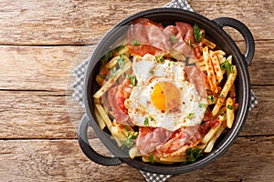 Huevos Rotos with fried potatoes and ham close-up in a plate. Horizontal top view photo