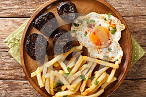Huevos Rotos Recipe: Spanish Broken Eggs with potato and blood sausage close-up in a plate. Horizontal top view photo