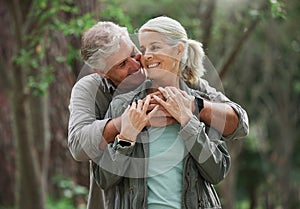 Hug, hiking and senior couple in nature with smile on adventure in forest, woods and mountain for exercise. Fitness