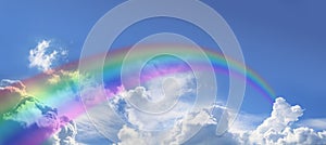 Huge arcing rainbow on wide blue sky