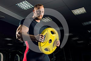 Huge athlete holds a disc for the bar