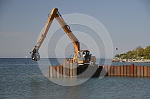 Huge backhoe drives pilings into the water