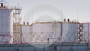 Huge big tanks at a large oil and patrol factory behind a biton fence with barbed wire