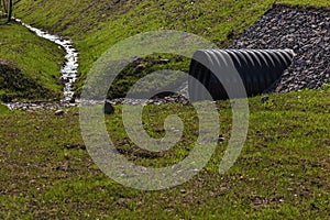 Huge black plastic sewer and small stream