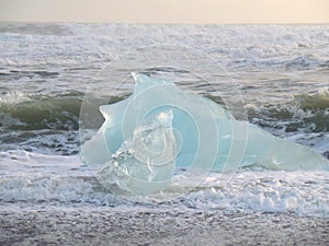 Huge blue iceberg against the waves on a windy day, Iceland