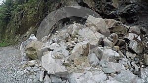 Huge boulder of solid rocks slide fall on rugged road side