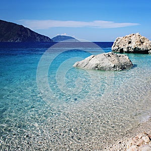 Huge boulders. Rocky shore. Small beach. Blue sea.