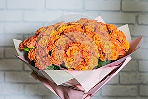 A huge bouquet of roses, against a background of a white brick wall.